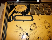 Image # 62113: KISS Partially Screened Backglass - Upper Left 
(First the mirroring was applied, then the black. This clear glass is resting upon brown paper.)