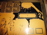 Image # 62114: KISS Partially Screened Backglass - Upper Right 
(First the mirroring was applied, then the black. This clear glass is resting upon brown paper.)