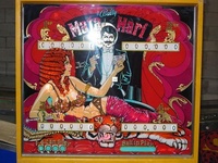 Image # 27825: Mata Hari Backglass with Dagger Inscription 
(This game has several serial numbers:1110 is stamped externally on both the cabinet side and head.1112 is tagged on the inside cabinet motor board.1113 is tagged inside the backbox.1116 is tagged under the playfield.)