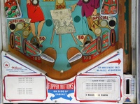 Image # 63442: Moulin Rouge Early Production Lower Playfield 
(The upside-down map depicted on the artist's easel is an after-factory adhesive. The mini-post between the flippers does not appear on the manufacturer's flyer and may be an after-factory addition. Serial number 19267.)
