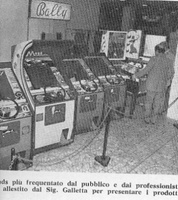 Image # 36803: Slap Stick Magazine Photo 
(From the Italian coin-op magazine Automat of a coin-op show held in Milan, Italy on April 14-25, 1975. In the background is a cabinet view of Bally's 1974 'Bali' bingo machine.)