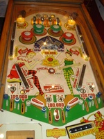 Image # 43117: Straight Flush Illuminated Playfield 
(The blue cover is missing from the roto-target assembly, revealing two light bulbs and their sockets. The outlanes between the flippers are missing their triangular cover.)