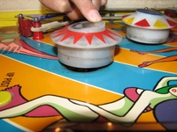 Image # 59679: Carnival Pop Bumper Activation 
(The pop bumper is manually operated to simulate a ball hitting it from the direction of the photographer's camera. A nearby pop bumper is in normal position. Serial number 0400.)