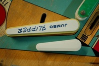 Image # 50840: Cowboy Jumbo Flipper Comparison 
(Gottlieb referred to their 3-inch flipper as a 'jumbo flipper' and it is shown here for size comparison. The Chicago Coin jumbo flippers on this playfield are reversed, causing the printing to be upside down.)