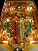 Image # 31094: Flipper Clown Sample Game - Illuminated Playfield 
(Center red and white roto-target lights are identified differently here than on production games. Serial number '01004 S' is stamped on outside of cabinet above the coin door.)